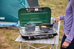 Wind-blocking panels shield burners while doubling as side tables.