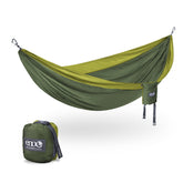 ENO DoubleNest hammock in olive-melon hangs between trees for relaxed outdoor lounging.