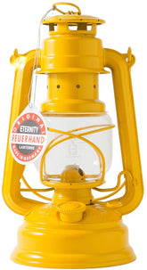 Feuerhand Baby Special 276 Signal Yellow lantern on a table casting a warm glow for outdoor evenings.