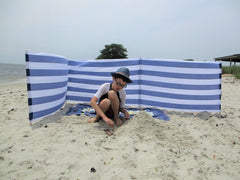 Blue white striped windscreen on the beach providing privacy and wind protection