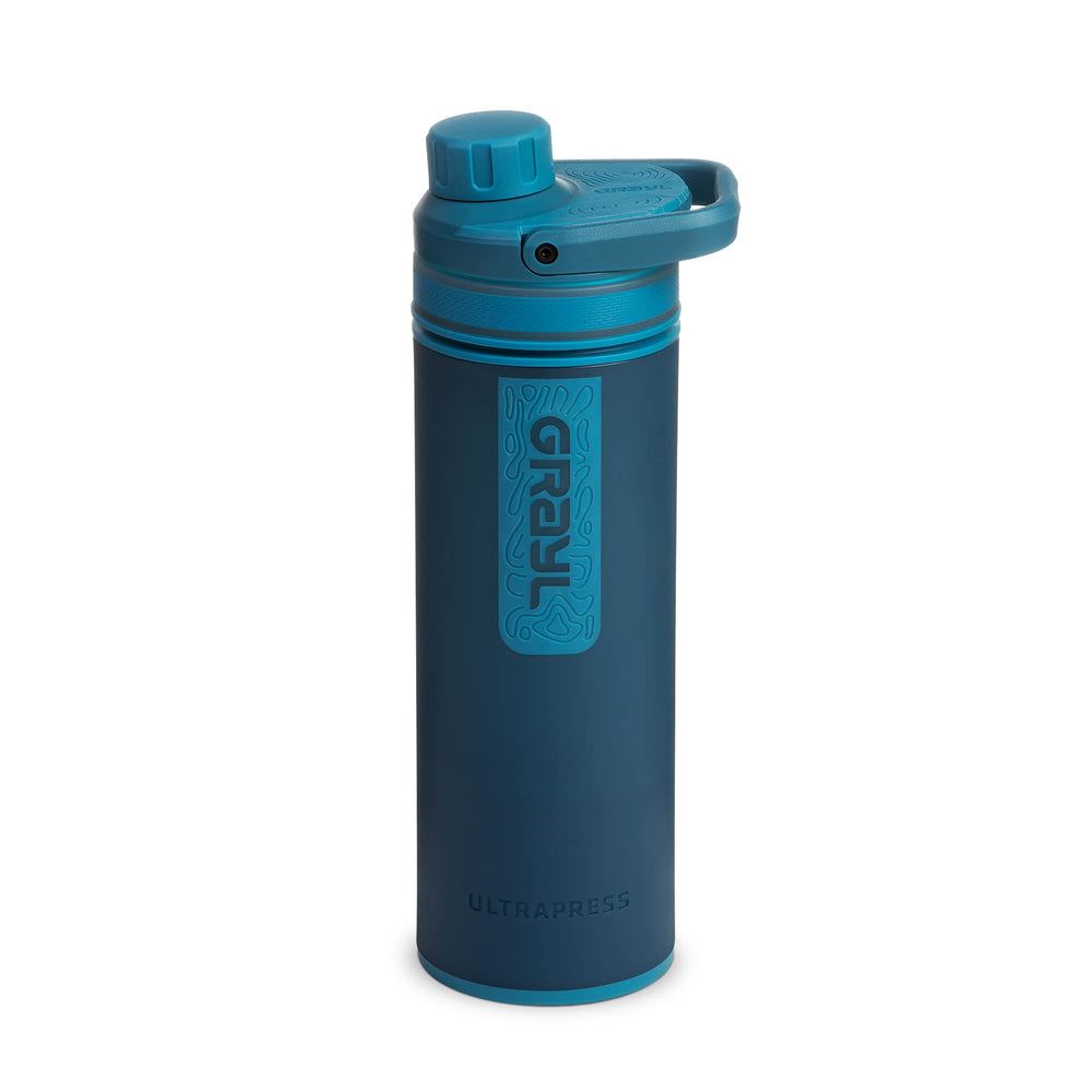 GRAYL UltraPress forest blue bottle filling from a river for safe hydration on the go.