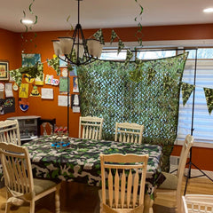 HYOUT woodland camo netting hung on a tree for concealment and shade.