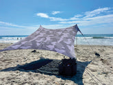 neso portable beach tent in setup mode with sand anchors for quick shade