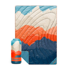 Rumpl Original Puffy Blanket in Teton Glow on campsite for all-weather warmth.