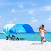 Shibumi Shade Mini on a sunny beach scene delivering portable shade for four.