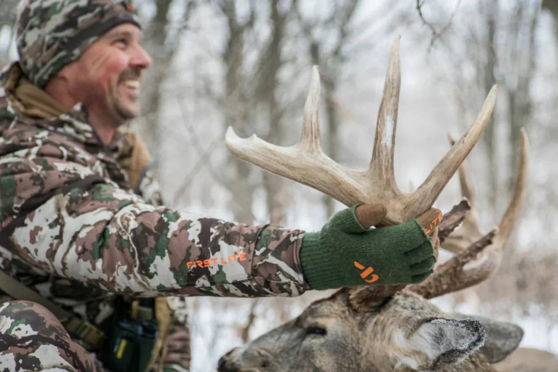 Smiling hunter holding a large whitetail deer antler in the winter forest, showcasing passion to become a better hunter.