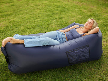 AlphaBeing inflatable lounger navy in use at the beach for comfortable, shade-free lounging.
