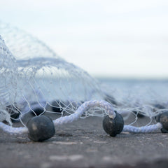 Cast net packaged in a heavy-duty 3.5 gallon bucket showing lead weights and brail lines