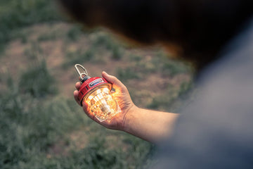 Barebones Beacon hanging light red cozy glow enhances backyard gatherings.