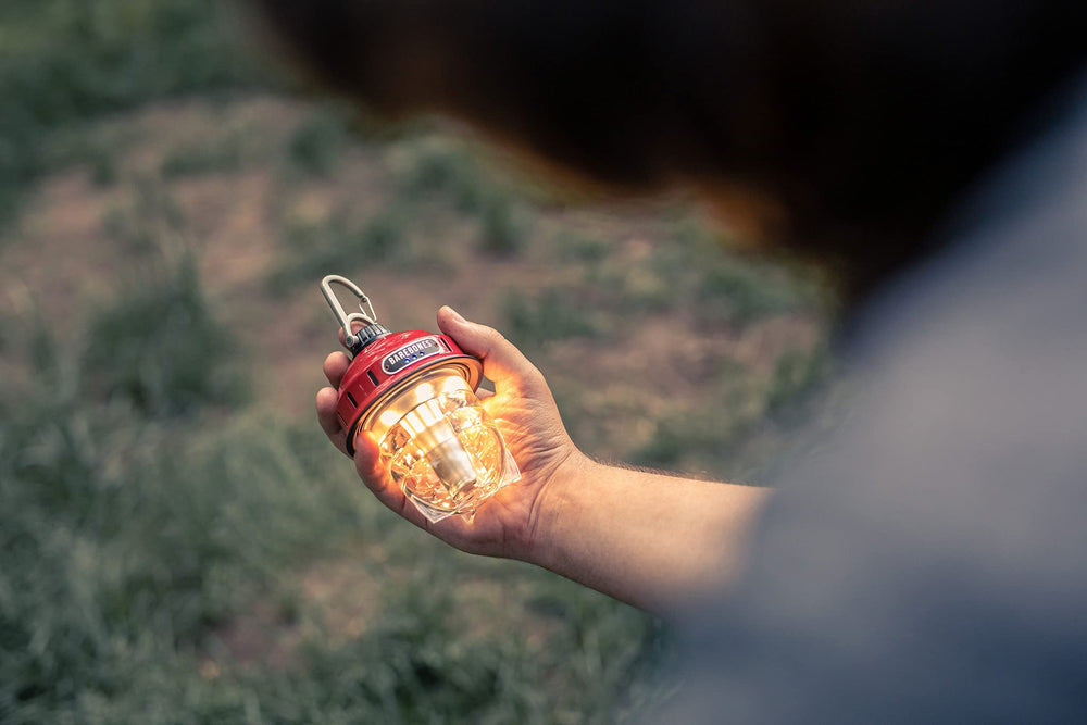 Barebones Beacon hanging light red cozy glow enhances backyard gatherings.