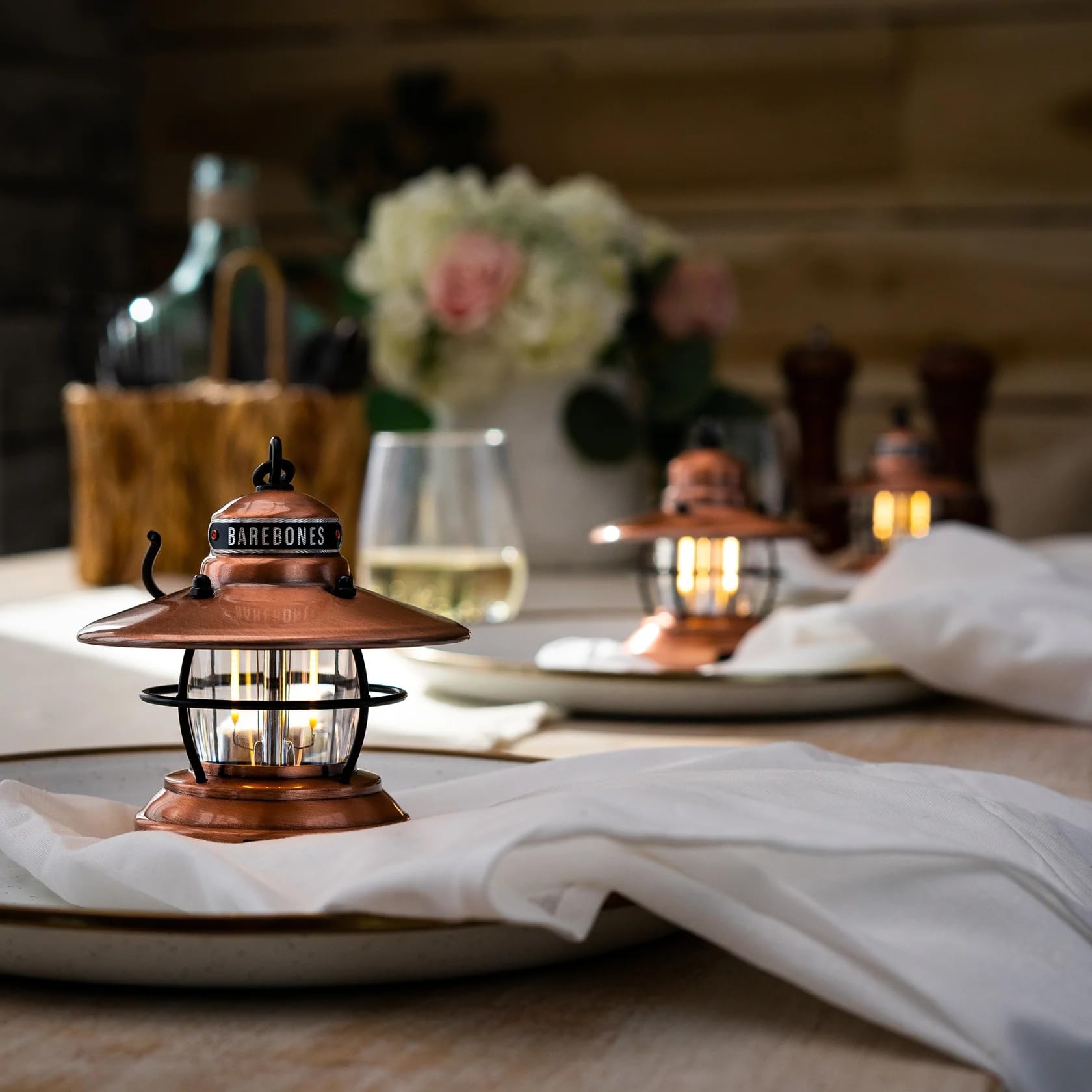 Barebones Edison Mini Lantern red glow near campsite table for decorative lighting.