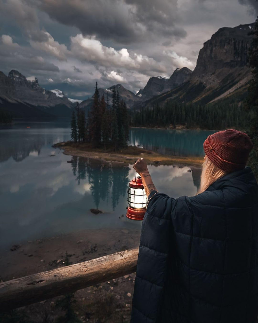 Barebones Forest Lantern red hanging on branch demonstrates versatile hanging options for cozy camp atmospheres.