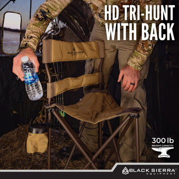 Black Sierra Equipment XL tripod hunting stool on rugged terrain shows stable seating.