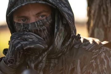 BLOCKER OUTDOORS Neck Gaiter worn in rugged terrain for concealment.
