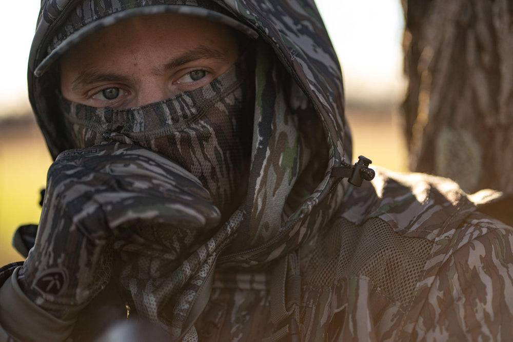 BLOCKER OUTDOORS Neck Gaiter worn in rugged terrain for concealment.