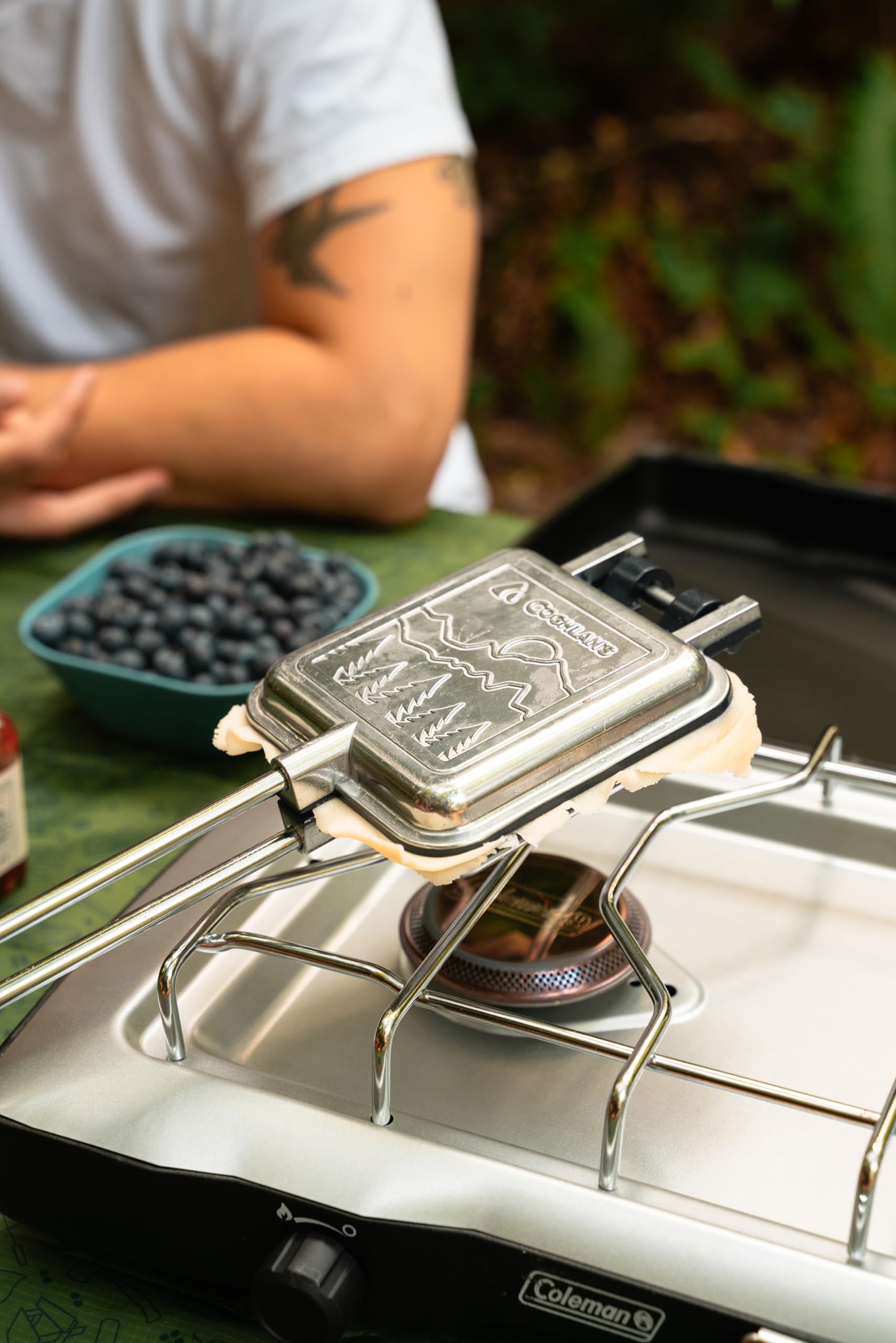 Coghlans camp cooker cooking over a campfire on a grill
