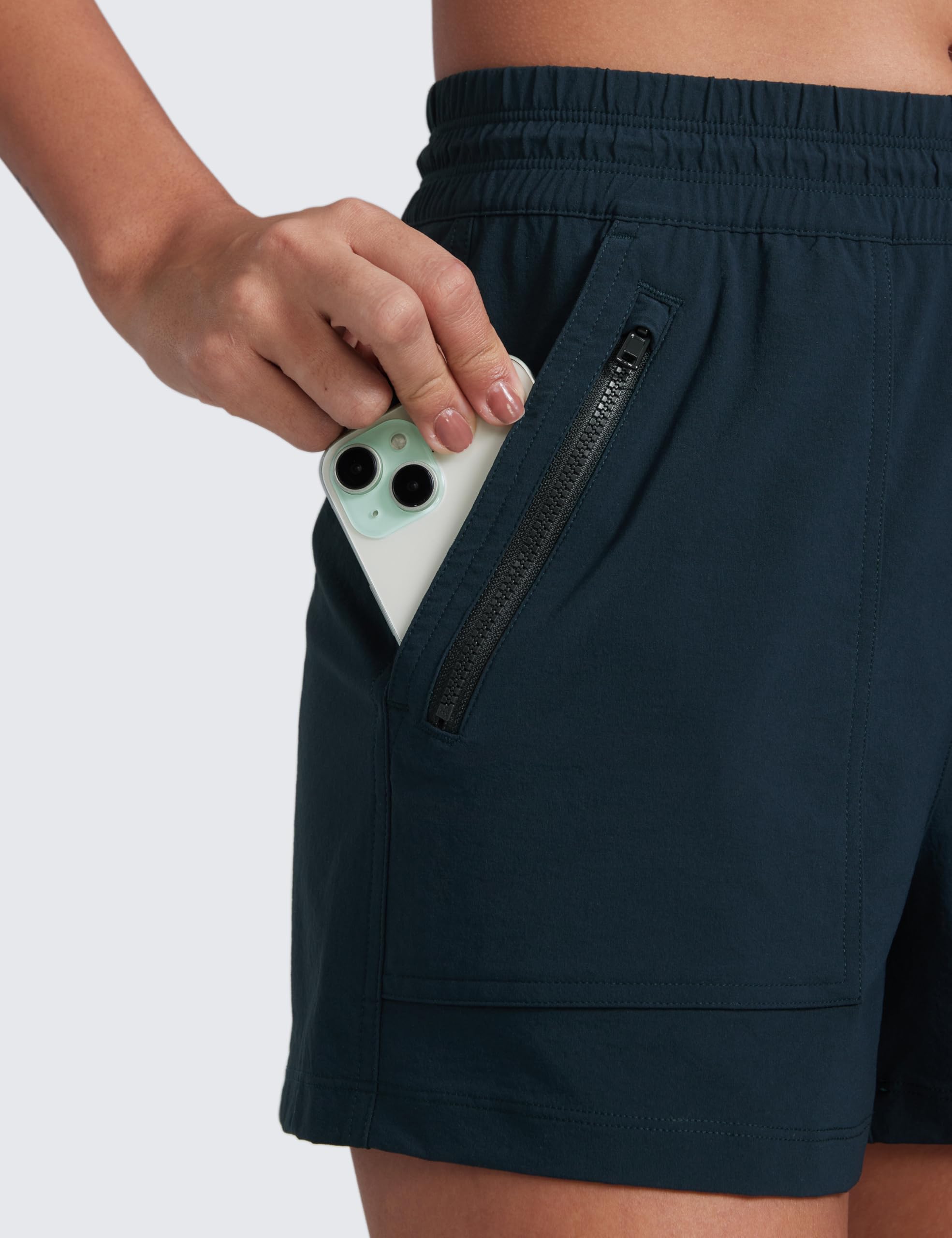 CRZ YOGA true navy shorts back pocket with zipper mesh pocket in use during travel.