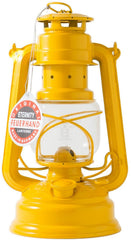 Feuerhand Baby Special 276 Signal Yellow lantern on a table casting a warm glow for outdoor evenings.