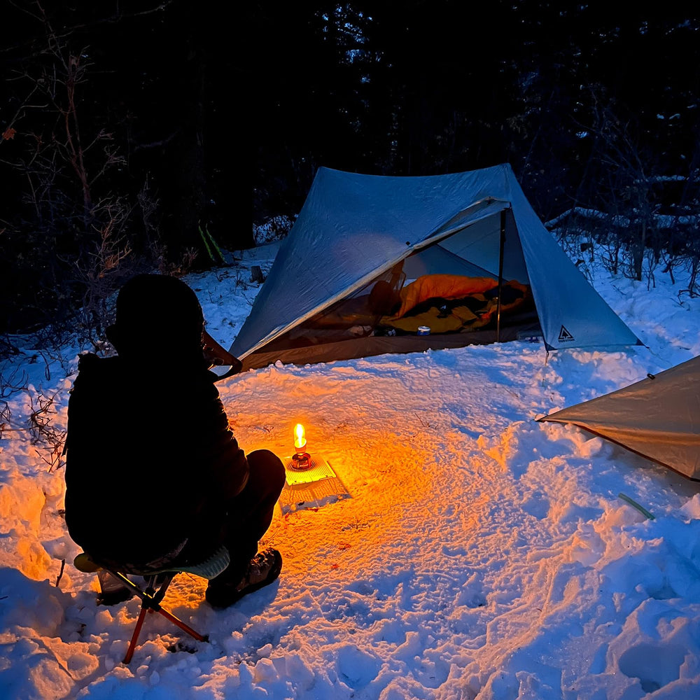 Fire-Maple orange camping lantern in use outdoors providing ambient light.