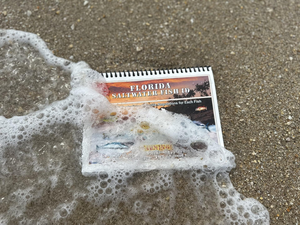 Compact spiral-bound waterproof Florida fishing guide in use by an angler