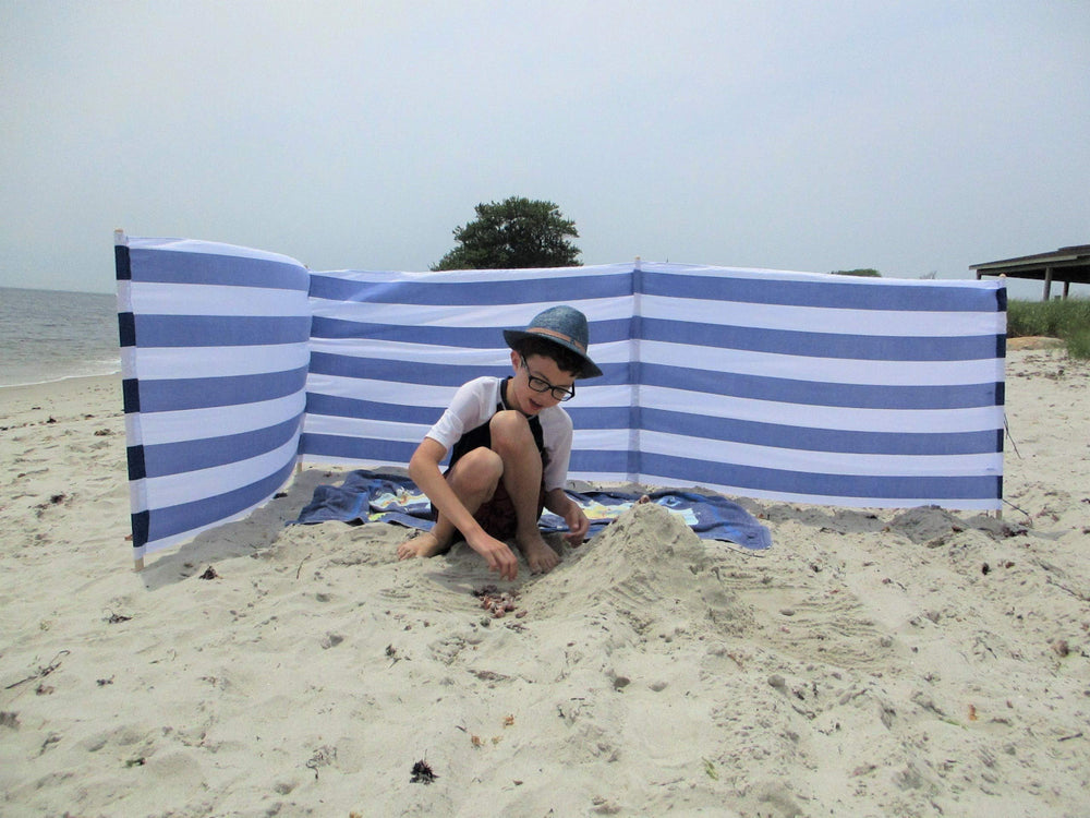 Blue white striped windscreen on the beach providing privacy and wind protection