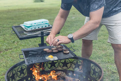 GameMaker grill and skillet combo cooking over a campfire for quick meals.