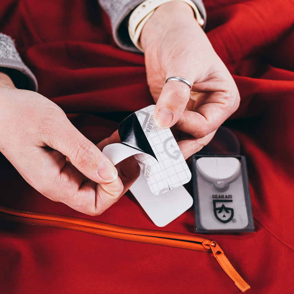 GEAR AID patches adhered to torn jacket fabric for quick repair