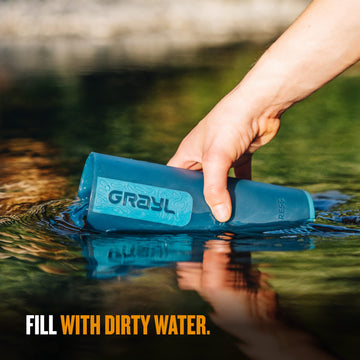 GRAYL UltraPress in use, pressing water from ground surface for clean drinking water.