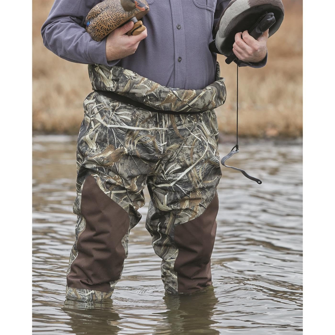 Guide Gear camo waders blend into marshy terrain for concealment.