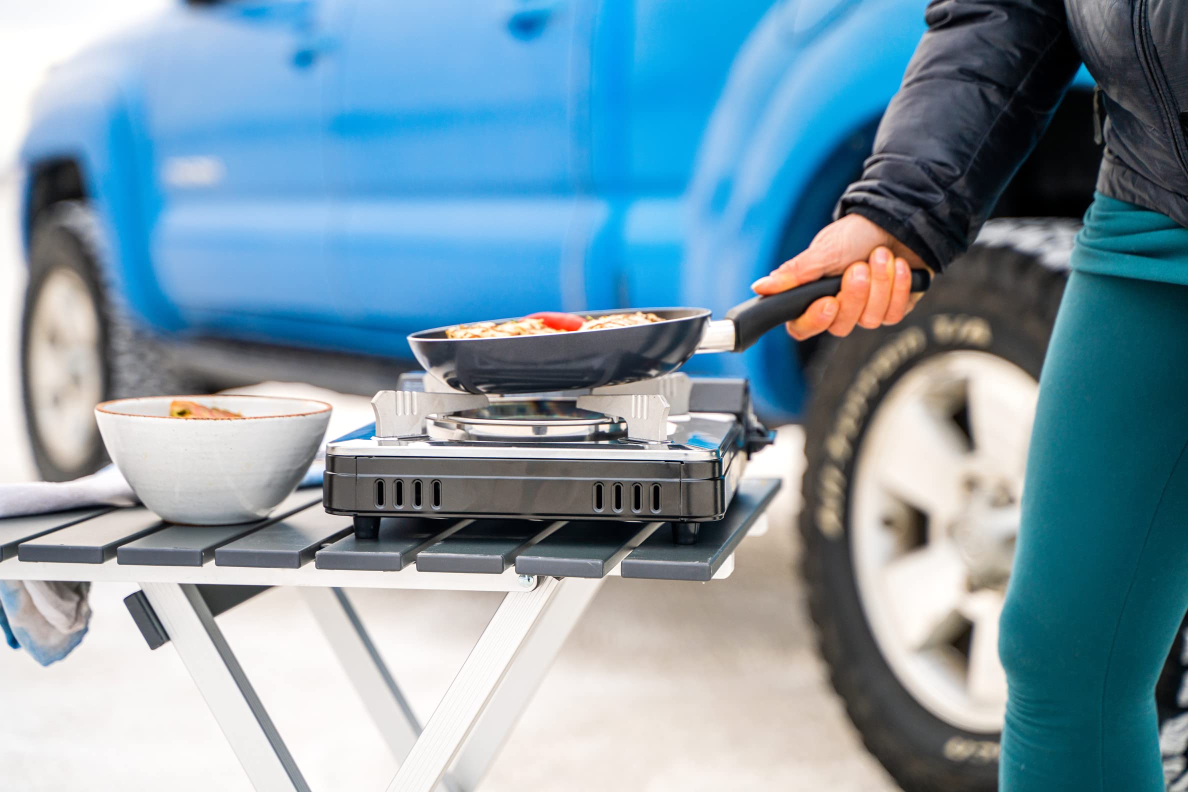 Iwatani Cassette Feu stove in use during camping scene illustrates outdoor meal prep.