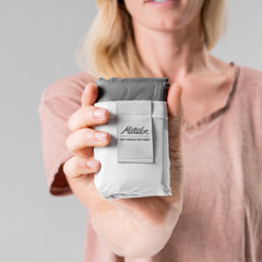 Matador Pocket Blanket 4.0 white laid flat in grass for picnic use.