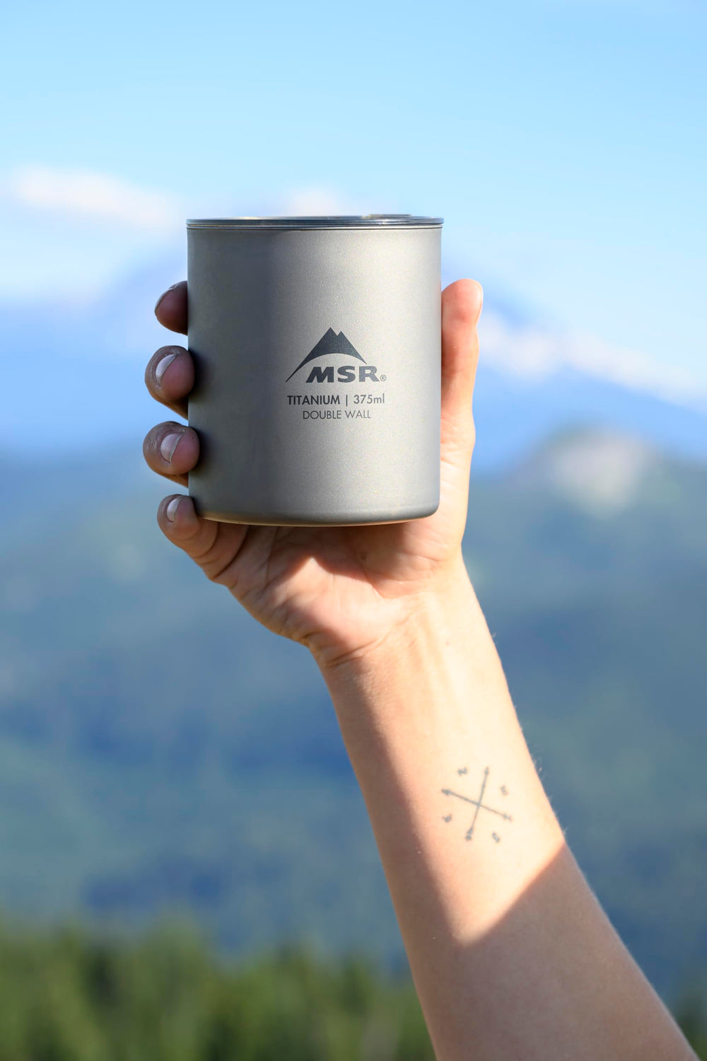 MSR Titan ultralight camp mug on campfire setup evokes backcountry coffee rituals.