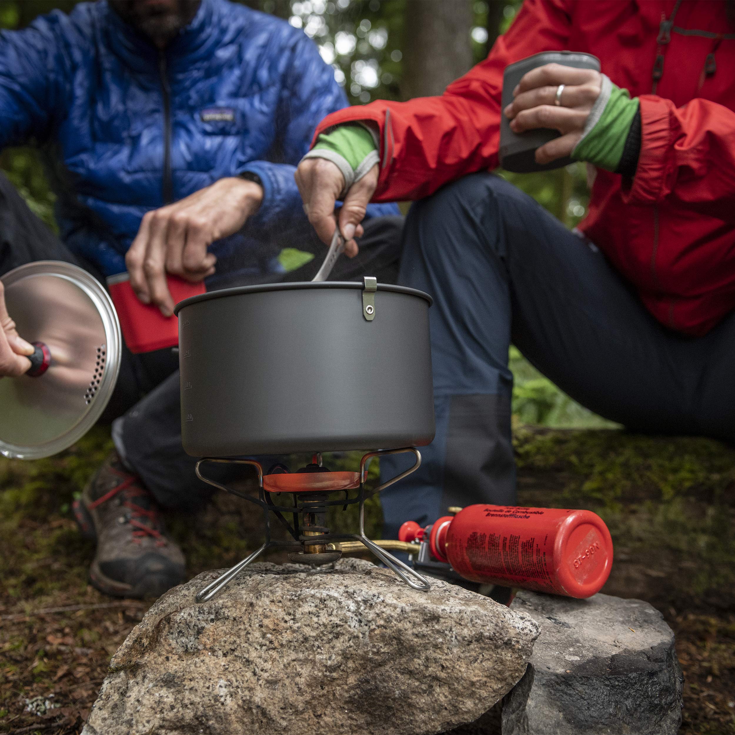 MSR WhisperLite Compact stove folded beside a pot, highlighting portability.