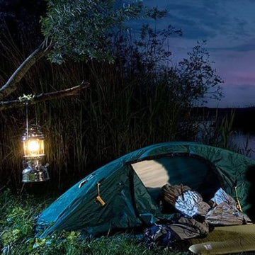 Outdoor camping scene with HK500 lantern on a trail, providing light after dusk