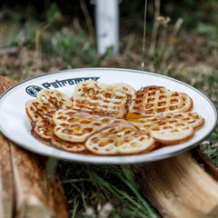 Petromax plate serving hot meals straight from the grill enhances outdoor dining.