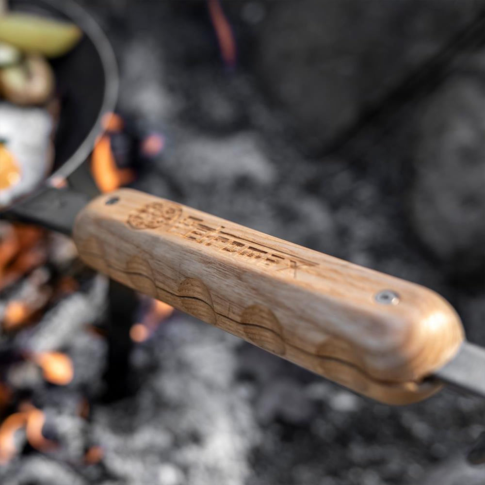 Wrought iron pan in use with Petromax handle for roasting over coals