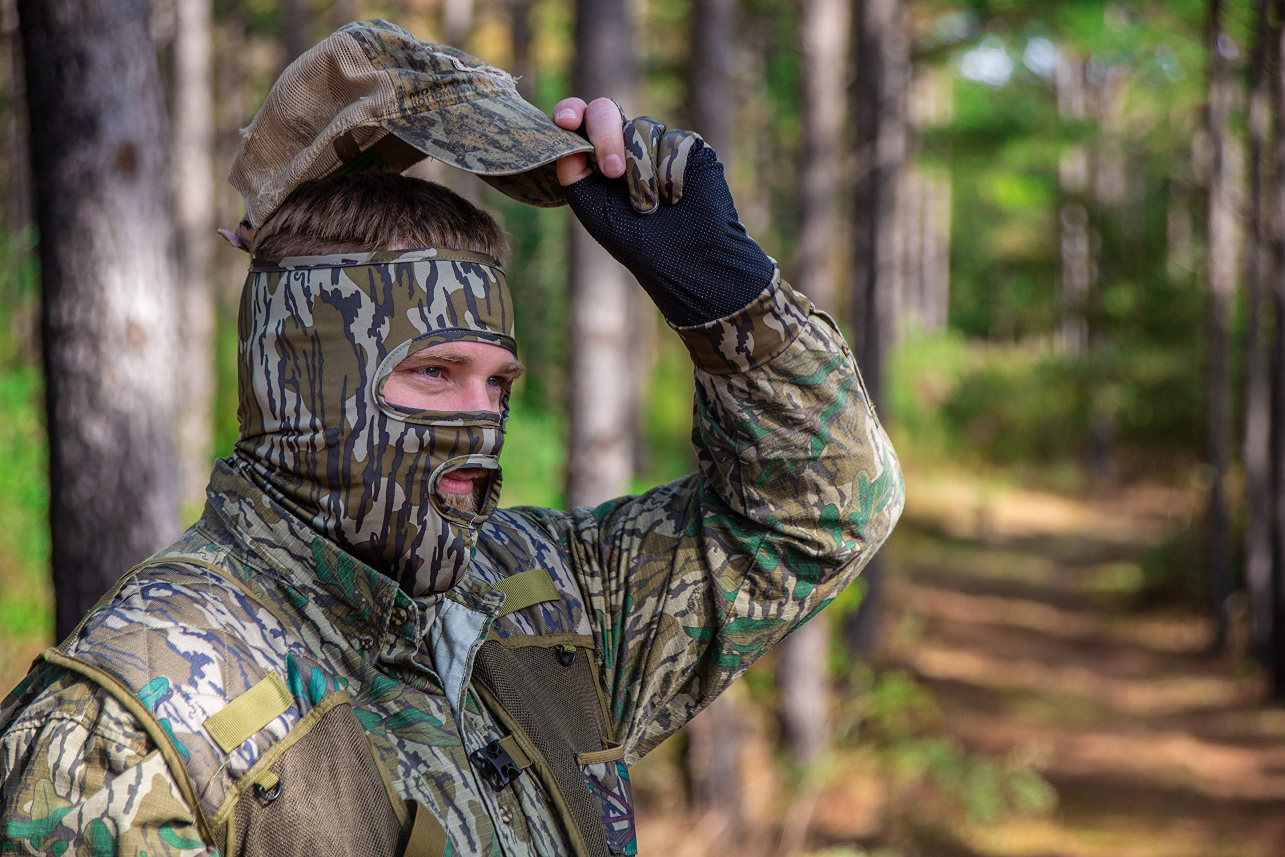 PRIMOS hunting mask in Real Tree camo blending into woodlands.
