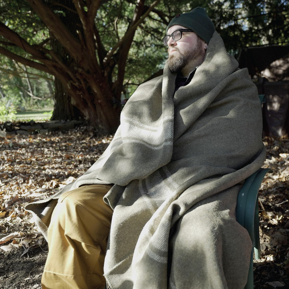 Rothco 22192 European surplus wool blanket on travel bag, ideal for picnics or warmth.