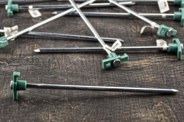 SE heavy-duty tent pegs anchored in dirt and grass for stability.