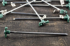 SE heavy-duty tent pegs anchored in dirt and grass for stability.