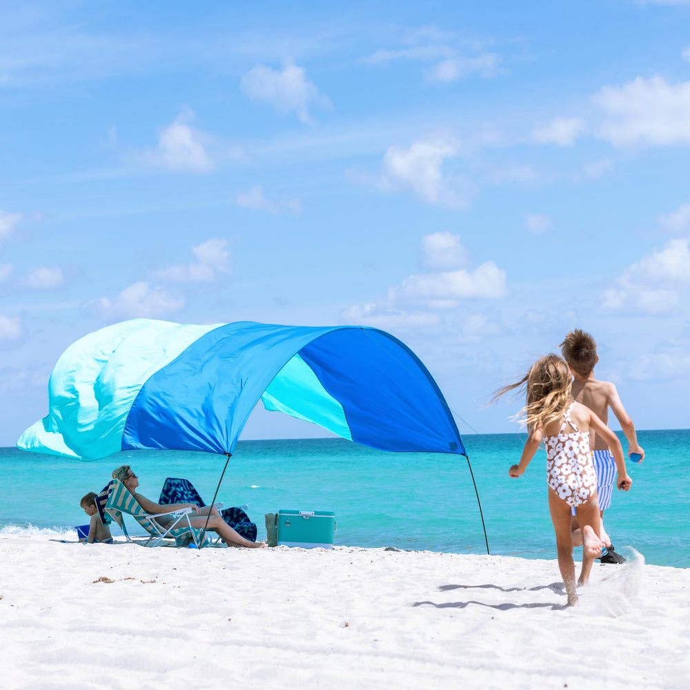 Shibumi Shade Mini on a sunny beach scene delivering portable shade for four.