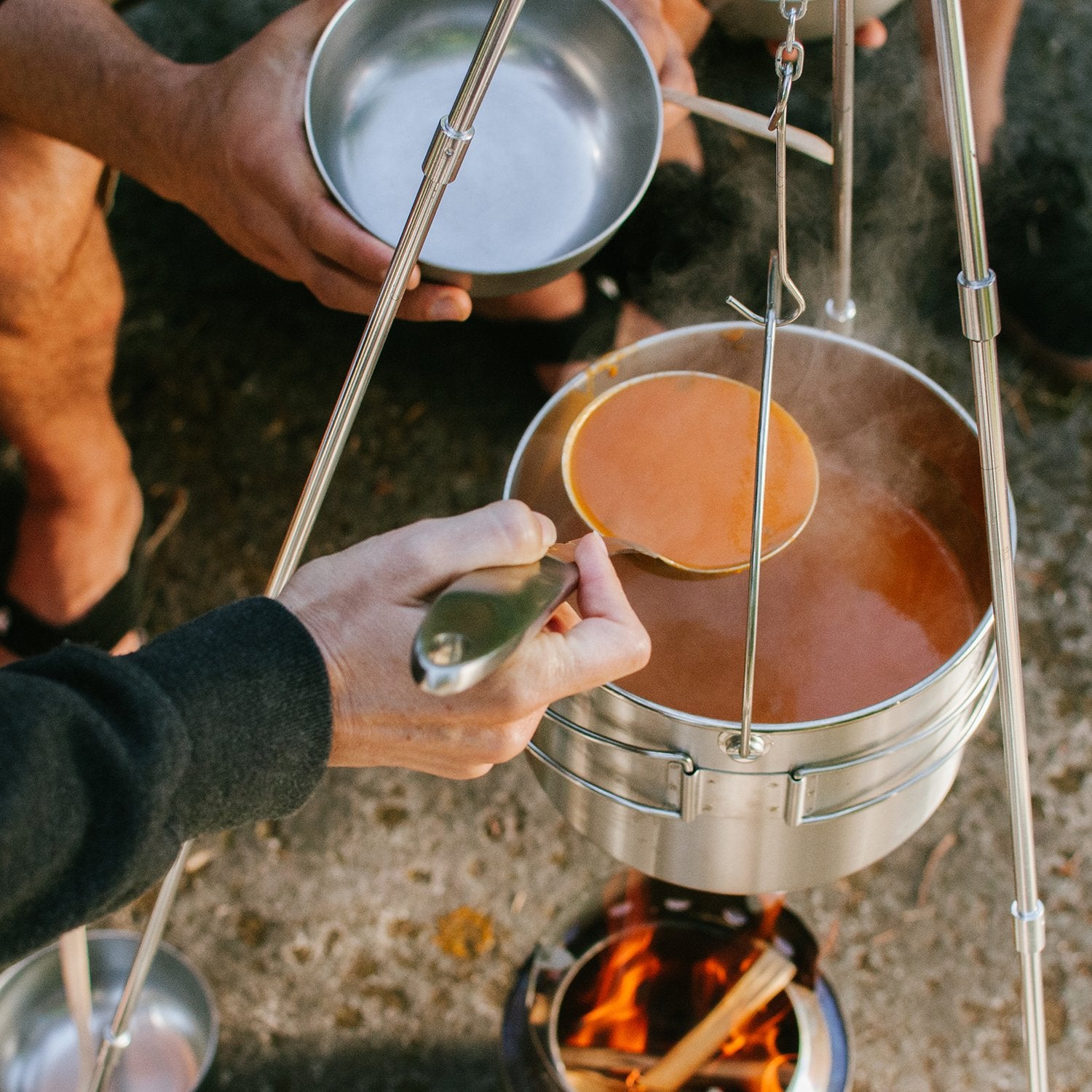 Solo Stove pot 1800 on tripod provides elevated cooking access over coals.