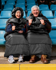Sportneer wearable sleeping bag hood-drawcord demonstrates snug warmth on chilly bleachers.