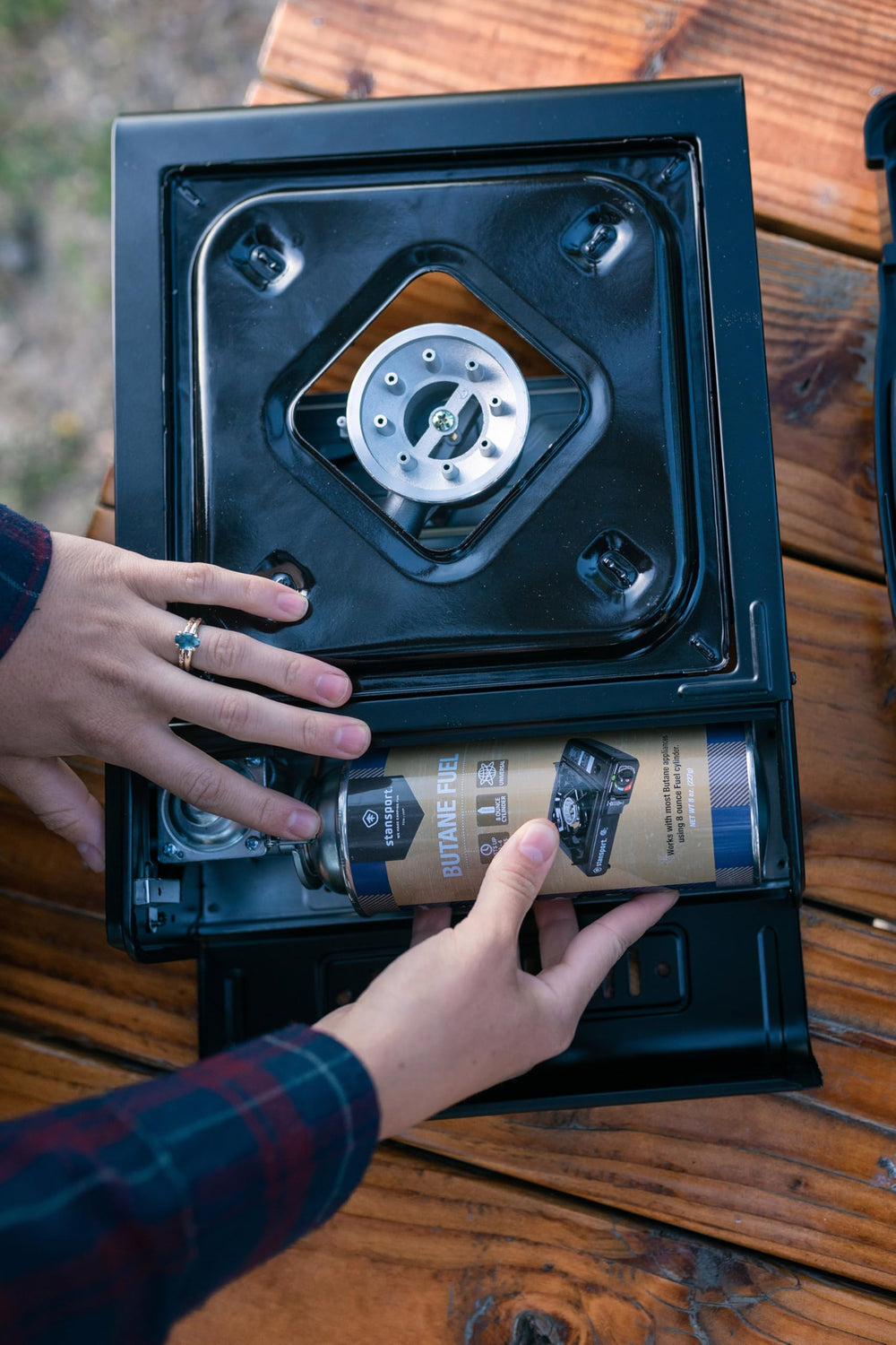 Stansport stove on camping table setup for on-site cooking.