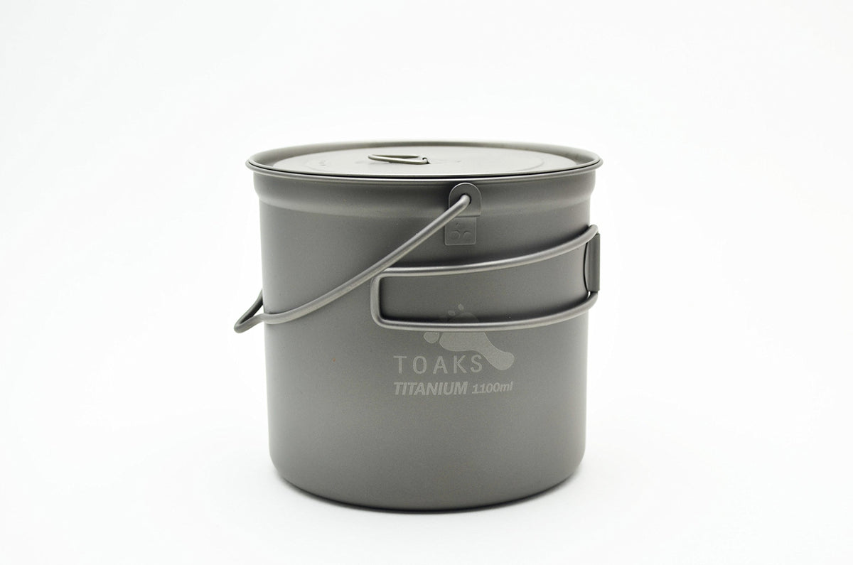TOAKS titanium 1100ml bushcraft pot with bail handle, ready for open-fire cooking.