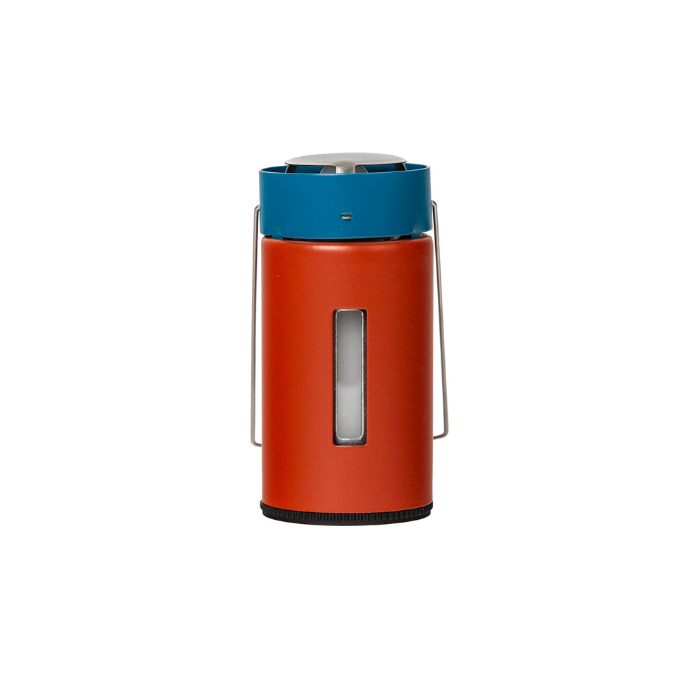 UCO Original Candle Lantern glows softly in a backyard or campsite setting.